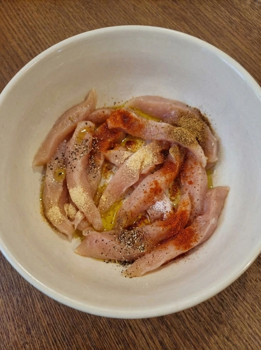 Raw chicken strips coated unevenly with spices