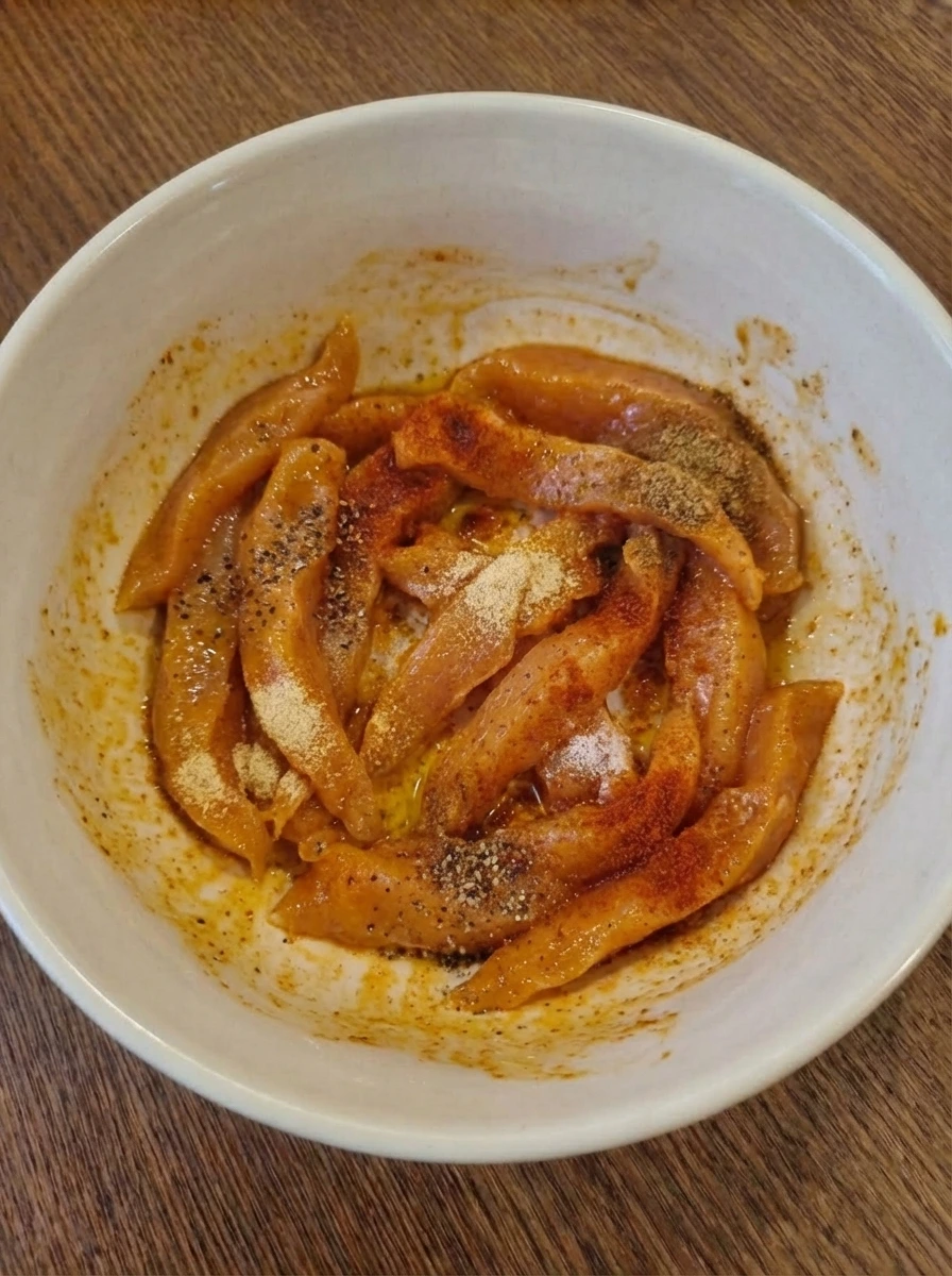 Marinated chicken strips coated with seasoning in a bowl
