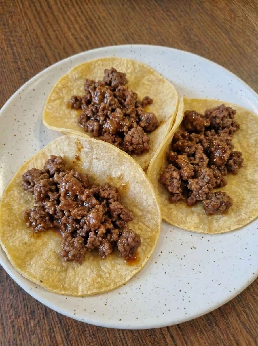 Warm tortillas filled with browned ground beef for tacos