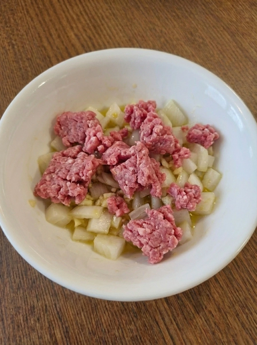 Raw ground beef added over onion and garlic for Easy Ground Beef Tacos