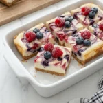 Easy Memorial Day Berry Cheesecake Bars with strawberries blueberries raspberries and crumb crust.