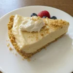 Easy No Bake Cheesecake slice on a white ceramic dessert plate with whipped cream and berries.