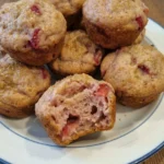 Easy Strawberry Muffins on a white plate with golden tops and juicy strawberry pieces