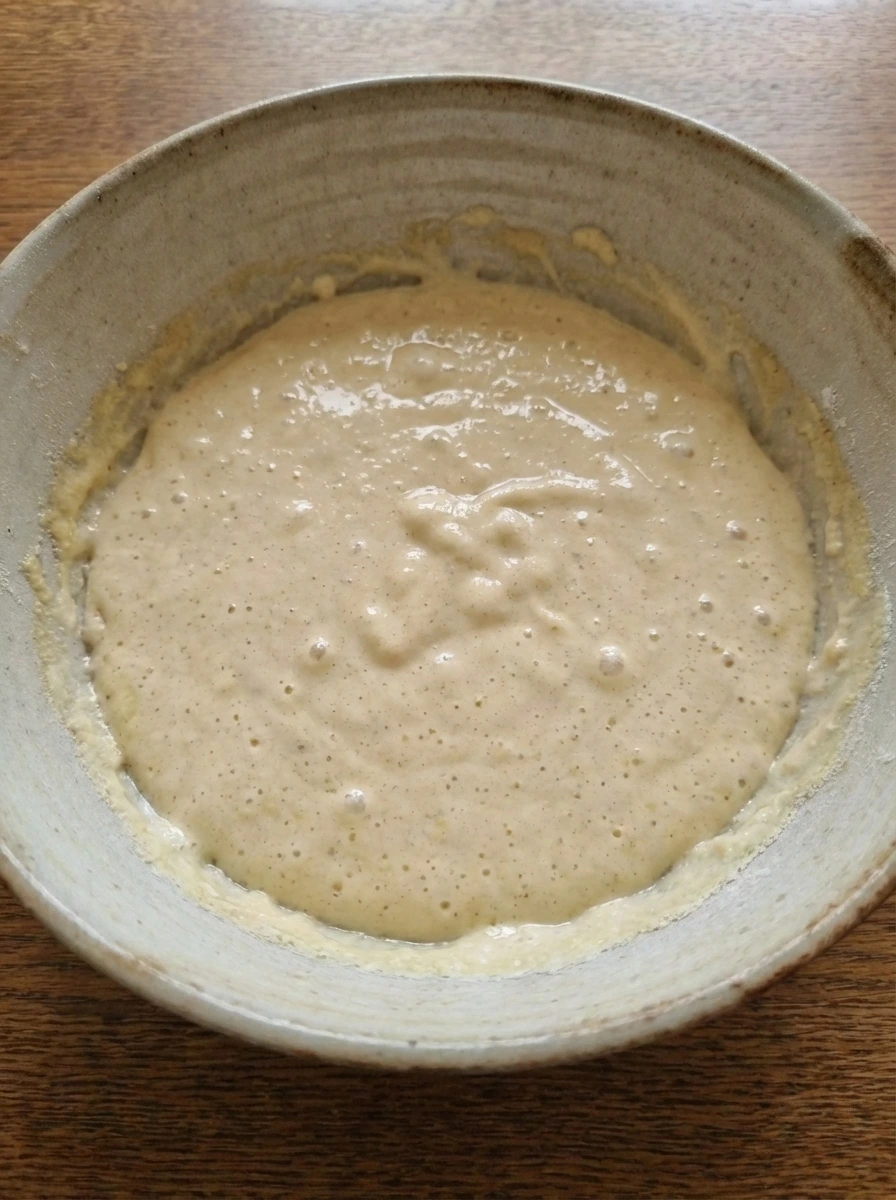 Rested pancake batter with tiny bubbles in a bowl