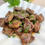 Garlic Butter Steak Bites on a white plate with browned edges and garlic butter glaze