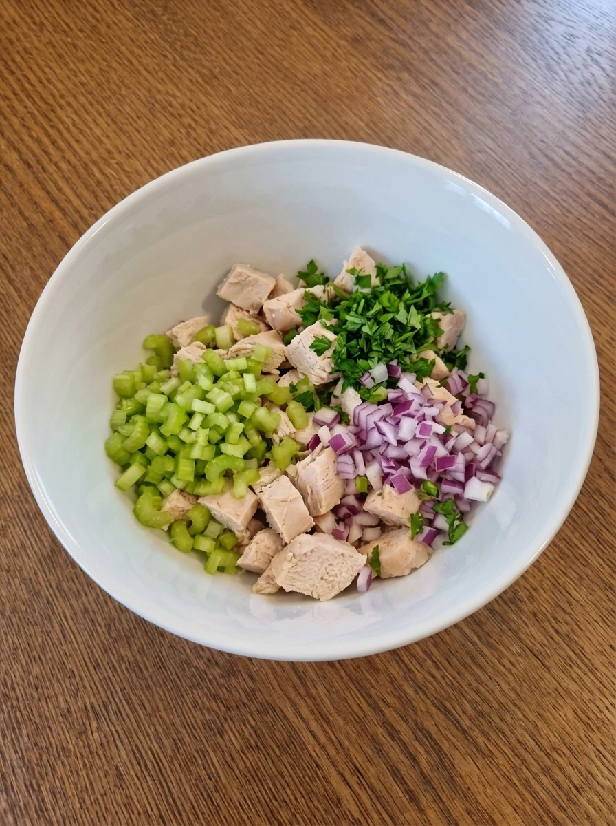 Chopped chicken celery onion and parsley in a white bowl