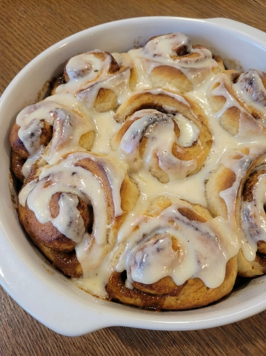 Finished Homemade Cinnamon Rolls with cream cheese icing in a white baking dish