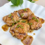 Honey Garlic Chicken Thighs on a white plate with sticky glaze and browned edges