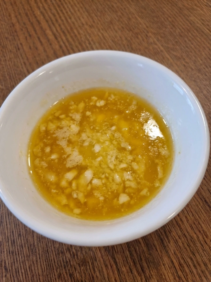 Glossy lemon garlic butter sauce with visible minced garlic in a white bowl
