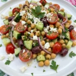 Mediterranean Chickpea Salad served on a white plate with feta olives cucumber and tomatoes