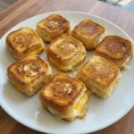 Mini Grilled Cheese Sliders on a white plate with golden tops and melted cheese.