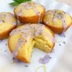 Mini Lemon Cakes with Lavender Glaze on a white scalloped dessert plate with uneven glaze and golden edges