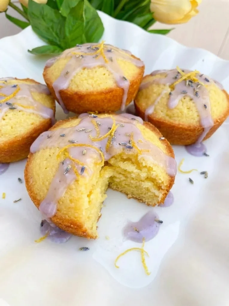 Mini Lemon Cakes with Lavender Glaze on a white scalloped dessert plate with uneven glaze and golden edges