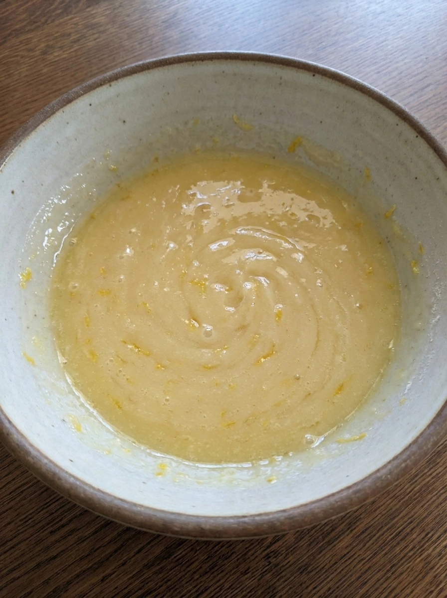 Wet ingredients blended for mini lemon cakes with lemon zest visible