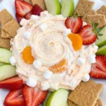 Orange Creamsicle Fruit Dip served in a white bowl with strawberries apples and graham crackers.