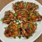 Oven Baked BBQ Chicken on a white oval stoneware plate with sticky glaze and browned edges