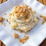 Pineapple Cheesecake Dip with toasted graham crumb and coconut topping on a white plate.
