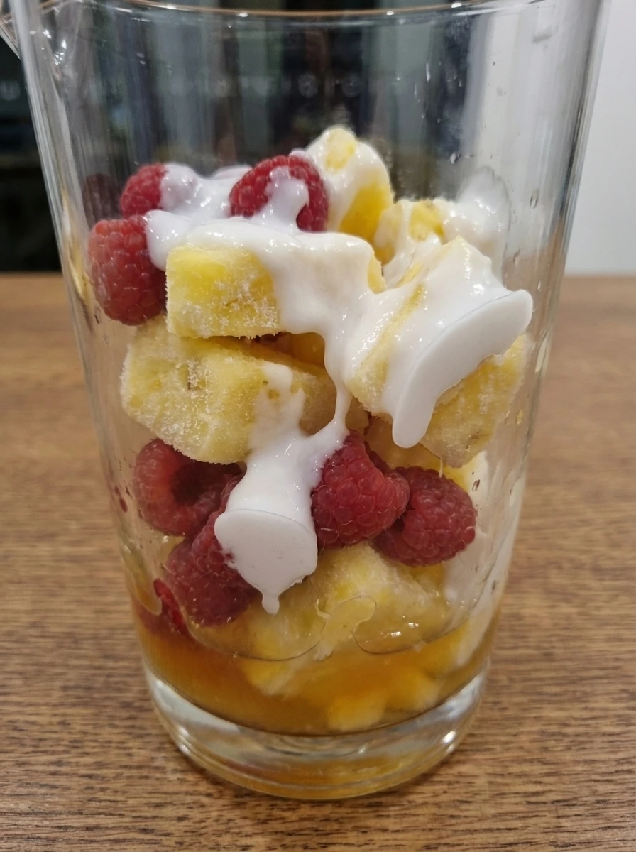 Layered raspberries pineapple coconut cream juice and rum before blending