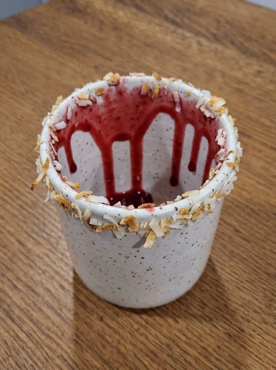 Glass swirled with raspberry syrup and coated with toasted coconut on the rim