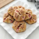 Golden Rhubarb Cheesecake Bombs with pink creamy filling showing through cracks