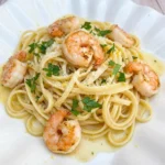 Shrimp Scampi Pasta on a white plate with garlic lemon butter sauce and parsley.