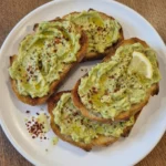 Simple Avocado Toast on a natural white stoneware plate with creamy avocado and golden toasted bread