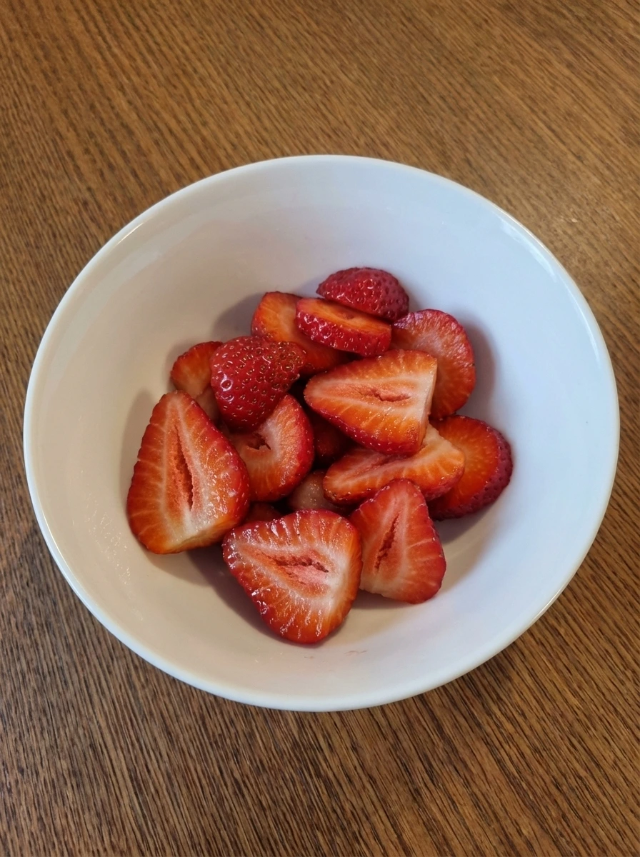 Unevenly sliced fresh strawberries in a natural white dish