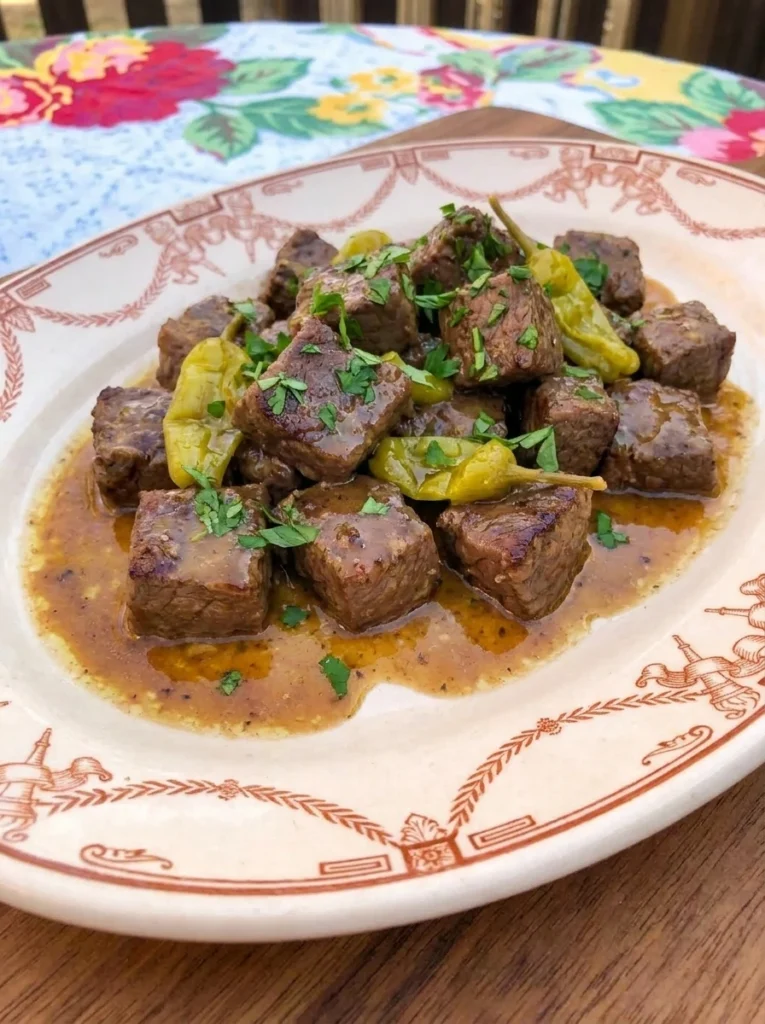 Slow Cooker Mississippi Steak Bites served on a plate with buttery pepperoncini sauce.
