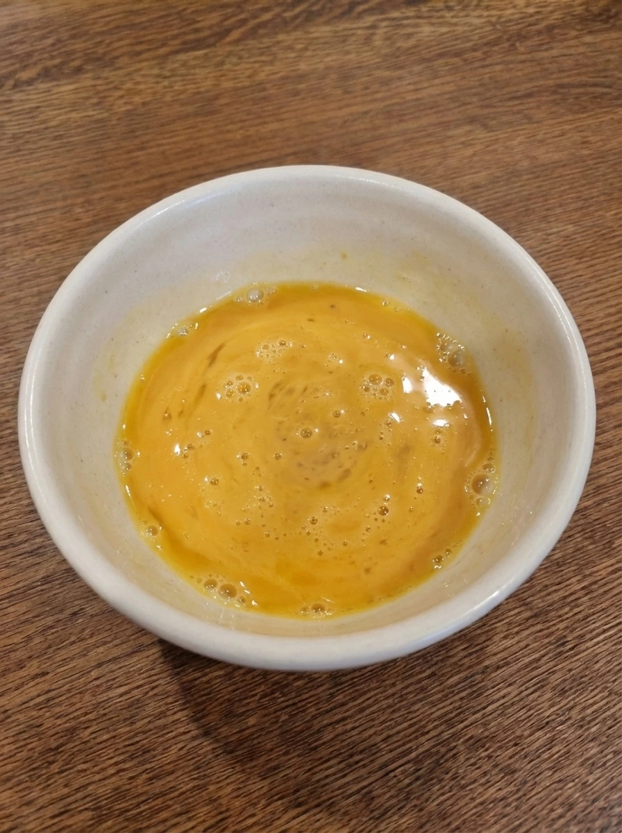 Whisked egg mixture for Soft Scrambled Eggs in a white dish
