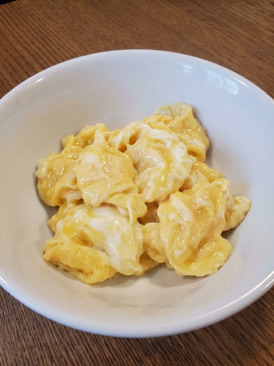 Loose glossy curds of Soft Scrambled Eggs in a white dish