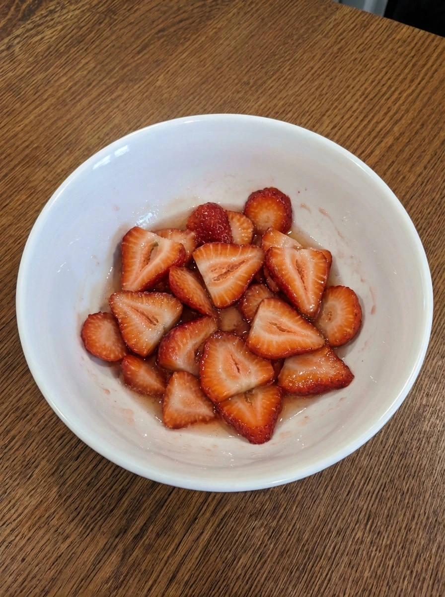 Sliced strawberries coated with sugar in a white dish