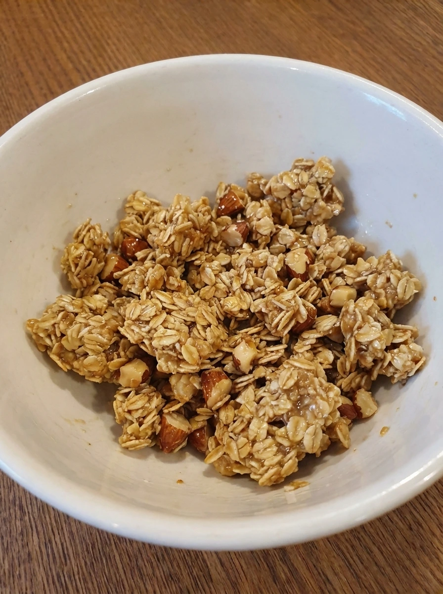 Oat almond brown sugar mixture forming rough crumb clusters in a white dish