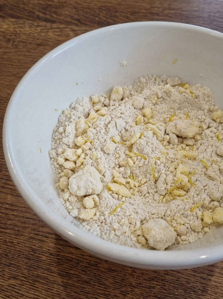 Crumbly flour and butter mixture with lemon zest in a white dish