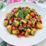 Strawberry Pineapple Salsa served on a white plate with charred pineapple strawberries lime and cilantro.