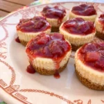 Strawberry Rhubarb Mini Cheesecakes with ruby fruit topping and graham cracker crust