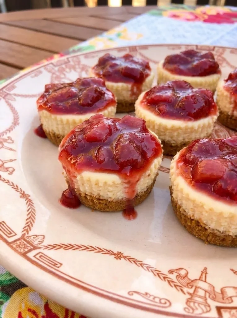 Strawberry Rhubarb Mini Cheesecakes with ruby fruit topping and graham cracker crust