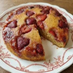 Strawberry Upside Down Cake on a white scalloped ceramic plate with glossy fruit and golden crumb