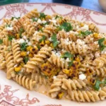 Street Corn Pasta Salad served on a white plate with charred corn cotija and cilantro.