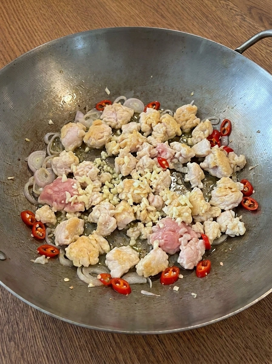 Ground chicken cooking with shallot garlic and red chilies in a wok.