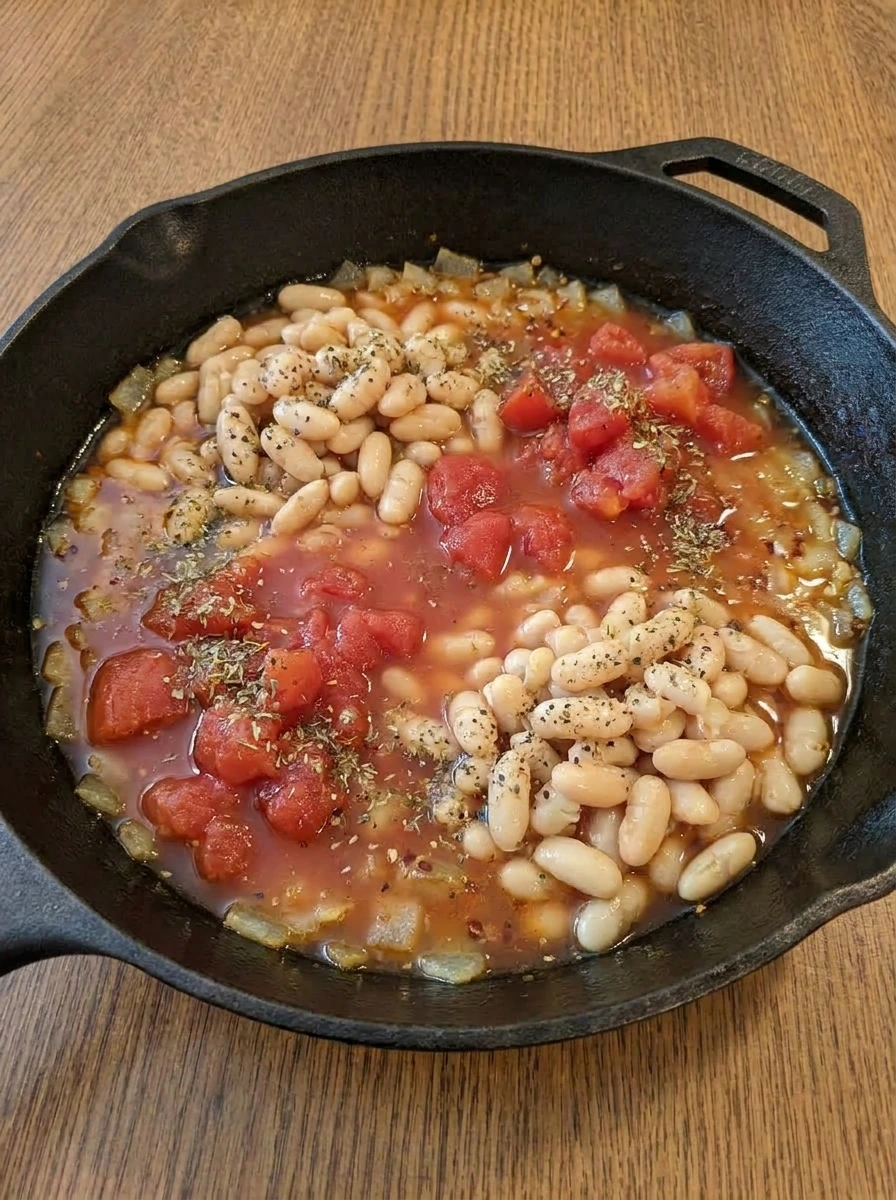 White beans tomatoes broth and herbs combined in the skillet.