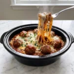 A plate of cheesy Slow Cooker Baked Spaghetti with meat sauce and fresh parsley garnish