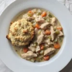 Chicken and Dumplings with Biscuits in a white bowl with golden biscuit pieces Recipe focus: chicken and dumplings recipe.