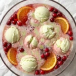 Christmas Sherbet Punch in a clear bowl with melting sherbet swirls and cranberry color Recipe focus: christmas punch with sherbet.