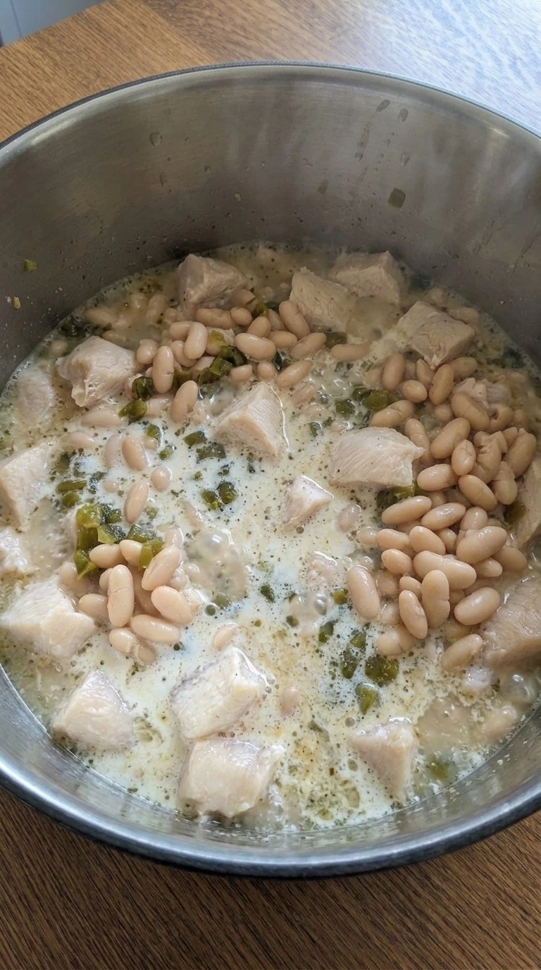 Creamy White Chicken Chili simmering with chicken and beans in a large pot Recipe focus: crockpot white chicken chili.