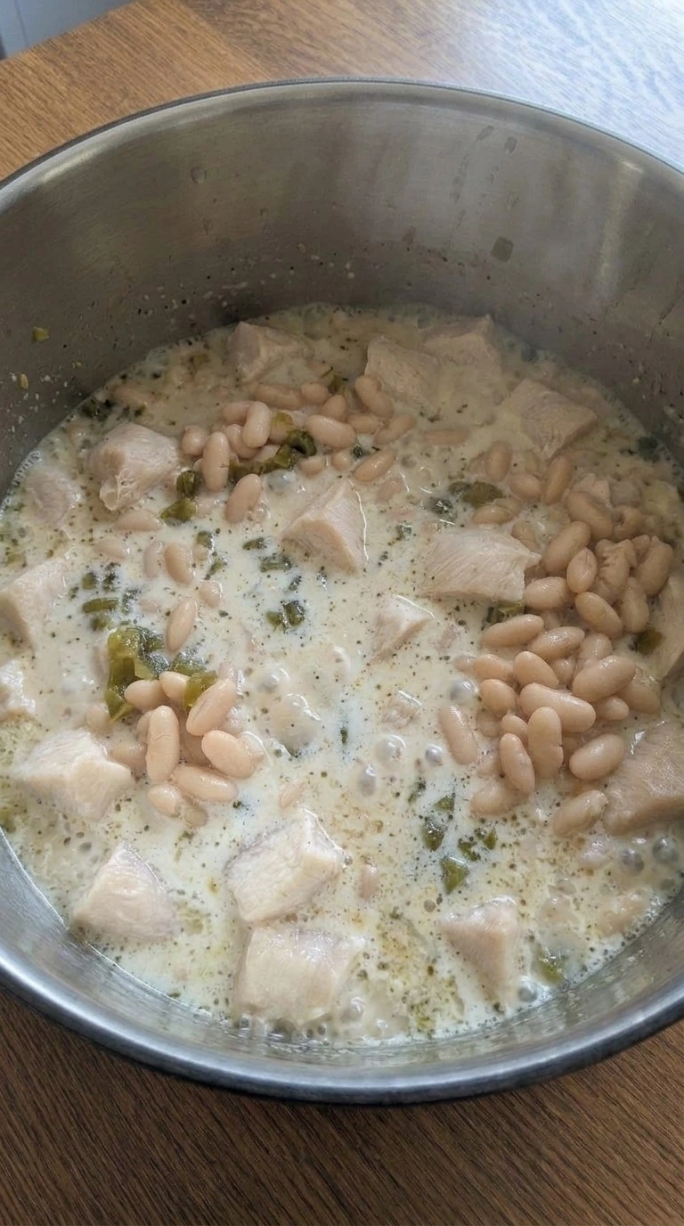 Creamy White Chicken Chili turning creamy after blending beans and adding dairy Recipe focus: crockpot white chicken chili.